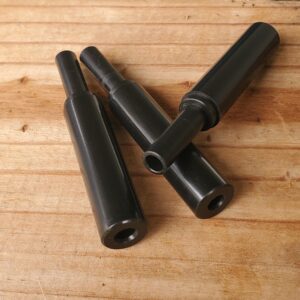 Three black plastic tube connectors laid on a wooden surface.